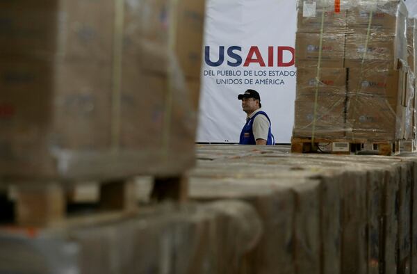 FILE - A man walks past boxes of USAID humanitarian aid at a warehouse at the Tienditas International Bridge on the outskirts of Cucuta, Colombia, Feb. 21, 2019, on the border with Venezuela. (AP Photo/Fernando Vergara)