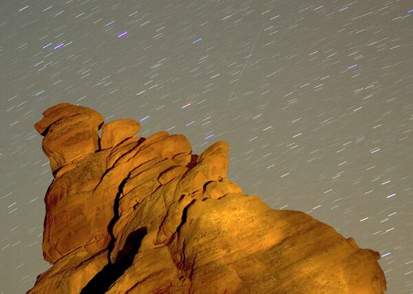 VALLEY OF FIRE STATE PARK, NV - DECEMBER 14: A Geminid meteor streaks diagonally across the sky against a field of star trails over one of the peaks of the Seven Sisters rock formation early December 14, 2007 in the Valley of Fire State Park in Nevada. The meteor display, known as the Geminid meteor shower because it appears to radiate from near the star Castor in the constellation Gemini, is thought to be the result of debris cast off from an asteroid-like object called 3200 Phaethon. The shower is visible every December. (Photo by Ethan Miller/Getty Images)