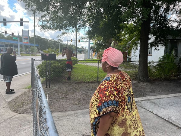 Jacksonville residents Patrick Sapp (left to right) Ron-reco Harris and Crecie Washington look at the police tape surrounding the Dollar General in their neighborhood on Sunday, August 27, 2023.