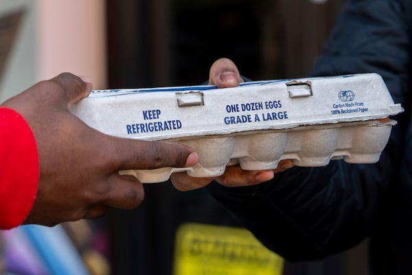 Abou Sow hands a free carton of eggs to a person , Friday, March 21, 2025, in the Harlem neighborhood of New York. (AP Photo/Julia Demaree Nikhinson)