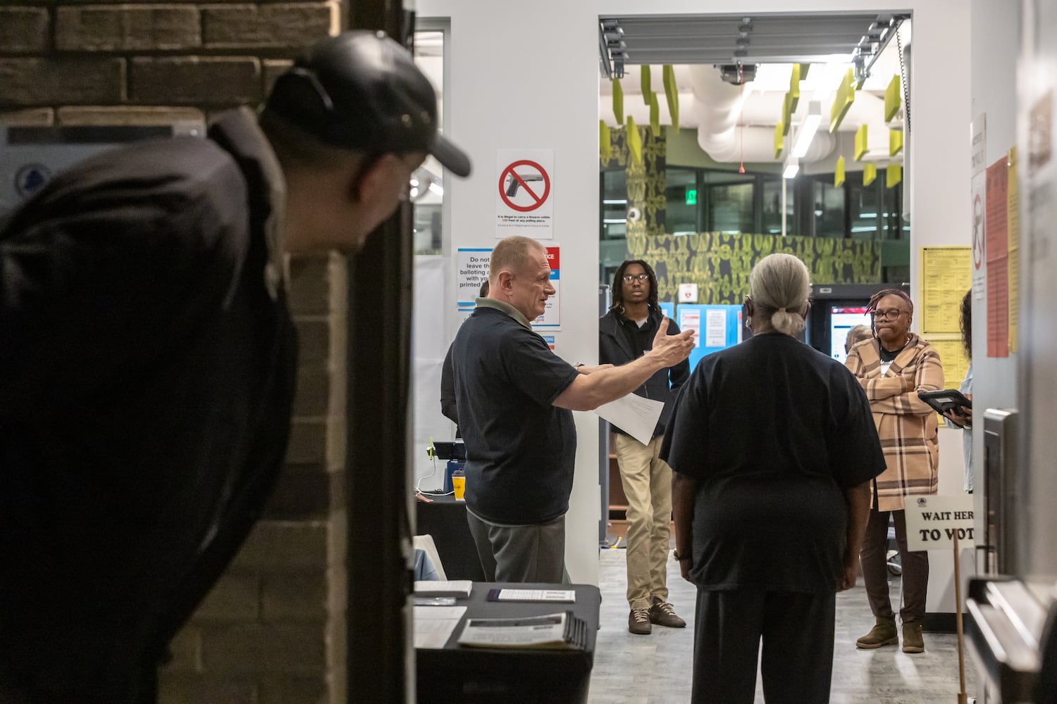 Poll manager, Dan Rauzi (center-left) directs traffic with other poll workers at the Joan P. Garner Library located at 980 Ponce De Leon Ave N in Atlanta on Tuesday, Oct. 15, 2024. Polling places opened for the first day of early voting Tuesday as Georgia prepares for another tour as one of America’s most hotly contested states. The state’s 8.2 million registered voters will consider important races up and down the ballot. (John Spink/AJC)