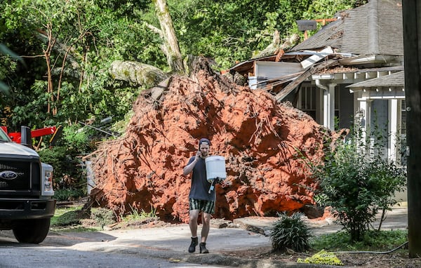 June 26, 2023 Smyrna: Kyle Rains begins removing items from his home on Monday morning June 26, 2023 after a tree that fell into the house overnight in Smyrna after thunderstorms moved across the area the night before, toppling trees and powerlines. Kyle Rains was playing with his 4-year-old son while his wife napped with their 10-month-old boy around 6 p.m. when they heard a crack. A few seconds later, there was a loud crash as a giant tree fell over their 113-year-old house. “I saw the branches in our side yard come over the house,” Rains told The Atlanta Journal-Constitution. The tree’s massive, overturned root system was as tall as the house. Its trunk had crushed the front of the century home and badly damaged its roof. the four year old was pretty upset. mainly worried about his Hot Wheels cars. Want to make sure they’re gonna be okay.As the sun came up Monday, more than 50,000 across the state were still without power, an improvement from the 155,000 outages reported by Georgia Power immediately following the deluge. Trees and limbs were down everywhere on several homes, on vehicles and across one of the busiest commuting arteries in Midtown Atlanta. In Midtown, a tree fell on West Peachtree Street at Spring Street, bringing down powerlines and closing the road at 17th Street. Authorities blocked 17th Street between West Peachtree and Peachtree streets as they worked to clear the tree.  (John Spink / John.Spink@ajc.com)

