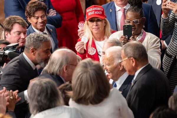 U.S. Rep. Marjorie Taylor Greene, R-Rome, attempts to hand President Joe Biden a Laken Riley pin ahead of his State of the Union address in Washington on Thursday.