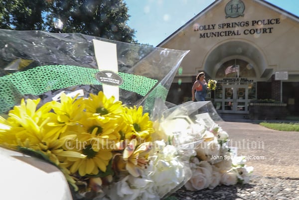 Amber Miller lays flowers at the Holly Springs Police Department building the morning after an officer was killed during a traffic stop.