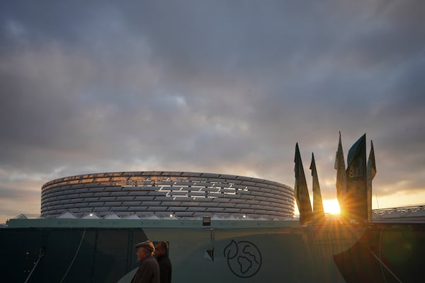 People walk with the Baku Olympic Stadium in the background during the COP29 U.N. Climate Summit, Wednesday, Nov. 20, 2024, in Baku, Azerbaijan. (AP Photo/Peter Dejong)