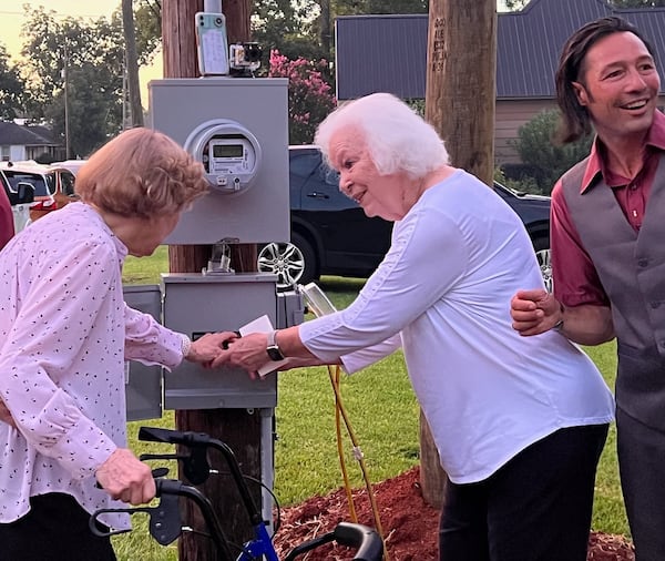 Former first lady Rosalynn Carter, with her sister Alethea Wall and Cody Munson, who helped install Dancing Monarchs, flips  the switch to officially open the sculpture.