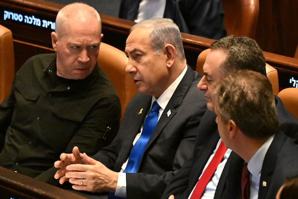 Israeli Prime Minister Benjamin Netanyahu, center, speaks to Defense Minister Yoav Gallant, left, at the opening of the 25th Knesset session marking the anniversary of the "Iron Swords" war, in Jerusalem, Monday, Oct. 28, 2024. (Debbie Hill/Pool Photo via AP)