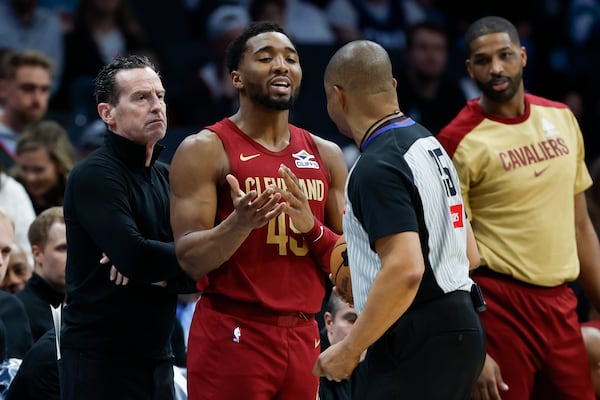 Cleveland Cavaliers guard Donovan Mitchell (45) steps between head coach Kenny Atkinson, left, and referee Tony Brothers, front right, during the first half of an NBA basketball game against the Charlotte Hornets in Charlotte, N.C., Friday, March 7, 2025. (AP Photo/Nell Redmond)