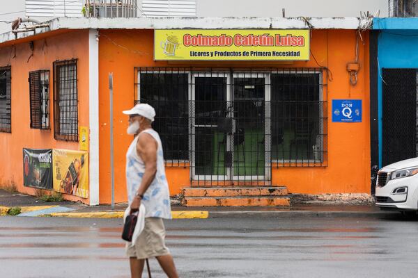 A local walks past a closed mini-market in Barrio Obrero, San Juan, Puerto Rico, Friday, March 14, 2025. (AP Photo/Alejandro Granadillo)