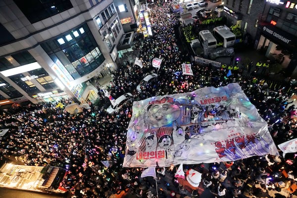 Participants hold a banner depicting South Korean President Yoon Suk Yeol's face on a cartoon train during a rally to demand his impeachment in front of the headquarters of the ruling People Power Party in Seoul, South Korea, Friday, Dec. 13, 2024. (AP Photo/Ahn Young-joon)