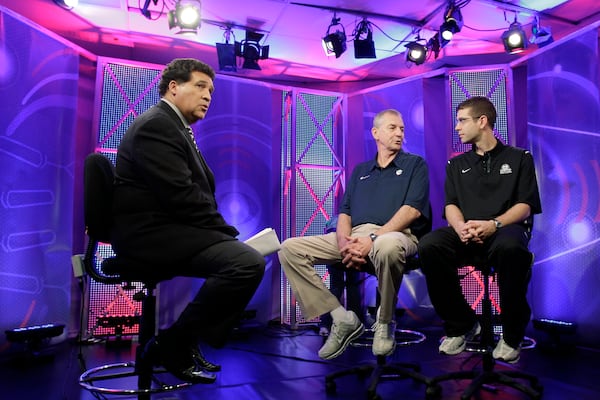 FILE - Greg Gumbel, left, watches as Connecticut head coach Jim Calhoun talks to Butler head coach Brad Stevens, right, prior to taping a television interview for the men's NCAA Final Four college basketball championship game Sunday, April 3, 2011, in Houston. (AP Photo/Eric Gay, File)