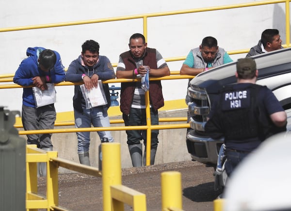 Handcuffed workers await transportation to a processing center following a raid by U.S. immigration officials at a Koch Foods Inc. plant in Morton, Miss. U.S. immigration officials raided several Mississippi food processing plants in early August and signaled that the early-morning strikes were part of a large-scale operation targeting owners as well as employees. AP PHOTO / ROGELIO V. SOLIS