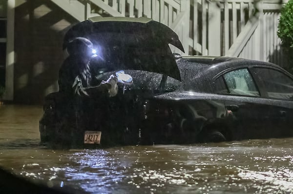 A car is partially submerged outside Peachtree Park apartments in north Atlanta before sunrise on Friday, Sept. 27, 2024.