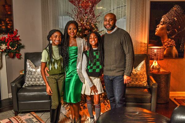 Chef Razia Sabour (second from left) is happy to be home for the holidays with her family, especially after being gone to film “The Great Soul Food Cook-Off,” a new cooking competition on Discovery+. She's shown with daughters Layla Burton (left, age 13) and Caden Burton (third from left, age 10) and husband Michael Burton. (Chris Hunt for the AJC)