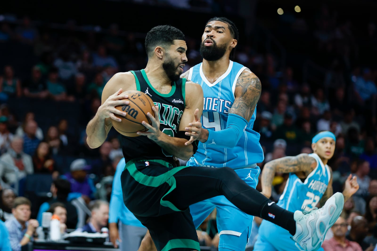 Boston Celtics forward Jayson Tatum, left, pulls down a rebound against Charlotte Hornets center Nick Richards during the first quarter of an NBA basketball game in Charlotte, N.C., Friday, Nov. 1, 2024. (AP Photo/Nell Redmond)