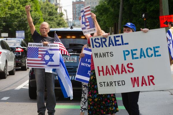 People wave to cars along  Spring St in front of the Israeli Consulate during a Pro Israel rally Sunday, May 23, 2021, in Atlanta.   STEVE SCHAEFER FOR THE ATLANTA JOURNAL-CONSTITUTION