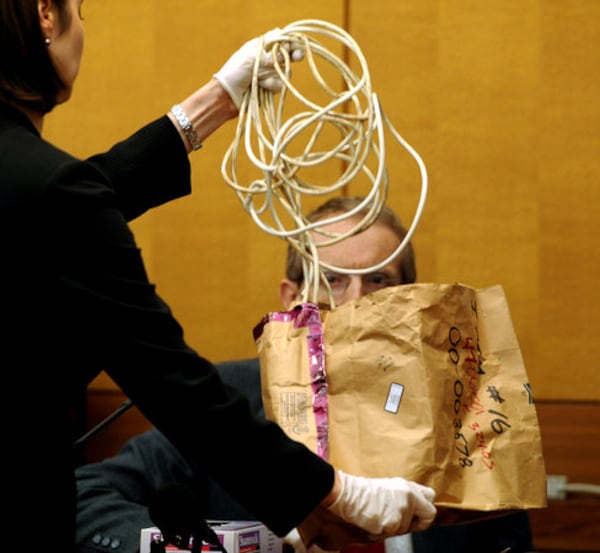 Fulton County prosecutor Sheila Ross, her hands gloved, shows a piece of evidence — an electrical cord from a vacuum cleaner — to Dr. Michael Henninger of the Fulton County Medical Examiner's office as Henninger testifies in the 2008 trial of Chiman Rai in Fulton County Superior Court. The cord was one of the items Cleveland Clark used in the 2000 slaying of Michelle "Sparkle" Reid Rai, prosecutors said. (AJC 2008)