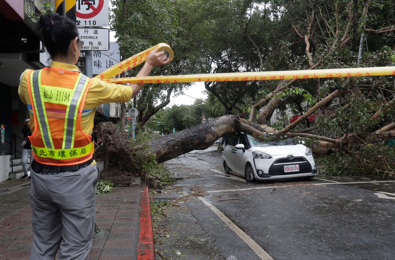 A sanitation worker of Taipei city government puts up a cordon at an area destroyed by the wind from Typhoon Kong-rey in Taipei, Taiwan, Friday, Nov. 1, 2024. (AP Photo/Chiang Ying-ying)