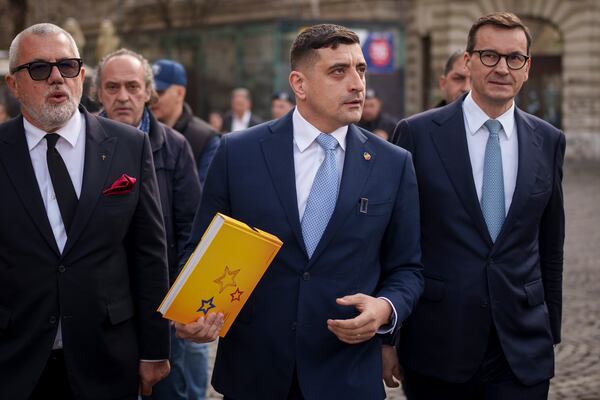 George Simion, the leader of Romania's most popular far-right party, the Alliance for the Union of Romanians (AUR), walks with former Polish Prime Minister Mateusz Morawiecki, right, in Bucharest, Romania, Friday, March 14, 2025, after filing his candidacy to participate in the country's presidential election rerun in May. (AP Photo/Vadim Ghirda)