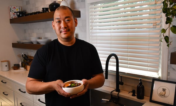 230320 Marietta, Ga: Chef Brian So in his Marietta home kitchen with one of his personal favorite meals, Dan Juk (Korean Congee) made his way, with soft boiled egg, scallions, crispy chicken skins, kosher salt, black pepper and spicy chili crisps. Photos for use with story on chef Brian So and his Dak Juk (Korean Congee) for AJC series At Home AAJC040623ATHOMECHEFBRIANSO Photo taken March 20, 2023 at the home of chef Brian So. (CHRIS HUNT FOR THE ATLANTA JOURNAL-CONSTITUTION)