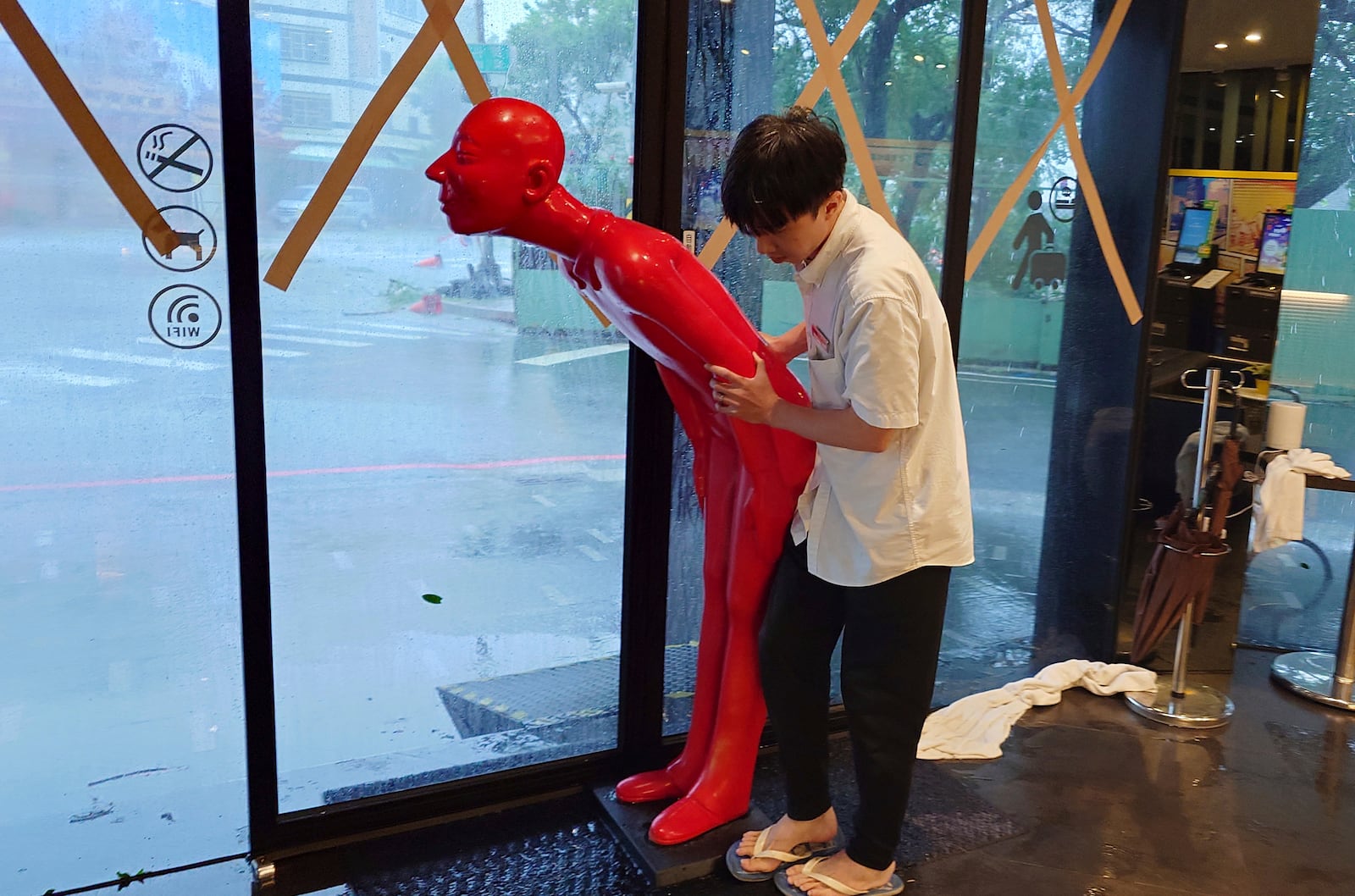 A hotel staff prepares to move a human figure from the doorway to inside as Typhoon Krathon arrives in Kaohsiung, southern Taiwan, Thursday, Oct. 3, 2024. (AP Photo/Chiang Ying-ying)