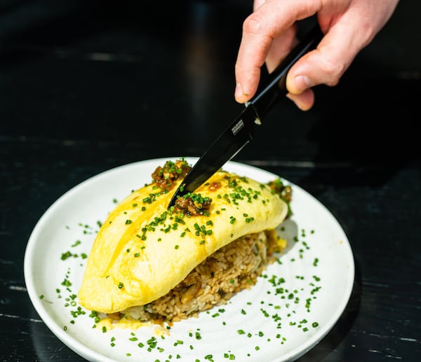 Here, co-executive chef Michael Bertozzi cuts open the Japanese-style omelet that tops the Blue Crab Fried Rice at Bully Boy, but the servers often take care of that task. CONTRIBUTED BY HENRI HOLLIS