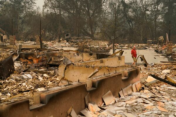 A man walks through a neighborhood destroyed by the Almeda Fire, Friday, Sept. 11, 2020, in Talent, Ore. (AP Photo/John Locher)