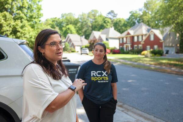 Brittany Peterson, left, and Jillian Scelsi stand across the street from the Powder Springs home where a man was arrested for illegally squatting after it became vacant. (Jason Getz / AJC)
