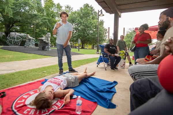 Gabriel Sanchez (center) and Kelsea Bond (ground) participate in a practice scenario at a summer heat safety training workshop in Atlanta on July 15. (Ziyu Julian Zhu / AJC)