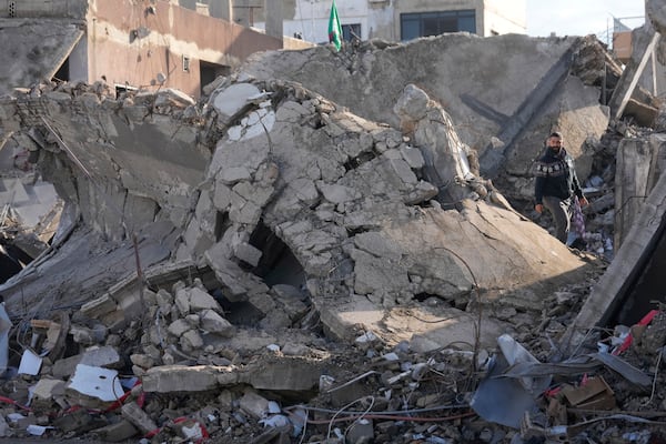 A man stands on the rubble of a destroyed building that housed his apartment in Tyre, southern Lebanon, Thursday, Nov. 28, 2024. (AP Photo/Hussein Malla)