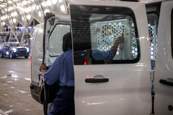 Immigrants and asylum seekers from Stewart Detention Center wait to be released from cages by a CoreCivic employee as they are dropped off in the curbside lanes of the domestic terminal at Atlanta's Hartsfield-Jackson International Airport, Thursday, Aug. 19, 2021. (Alyssa Pointer/Atlanta Journal Constitution)