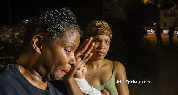 Alicia Willis (left) grieves as cousin Audrey Gross holds 11-month-old Landon Cree outside the scene of a deadly triple shooting in DeKalb County. JOHN SPINK / JSPINK@AJC.COM