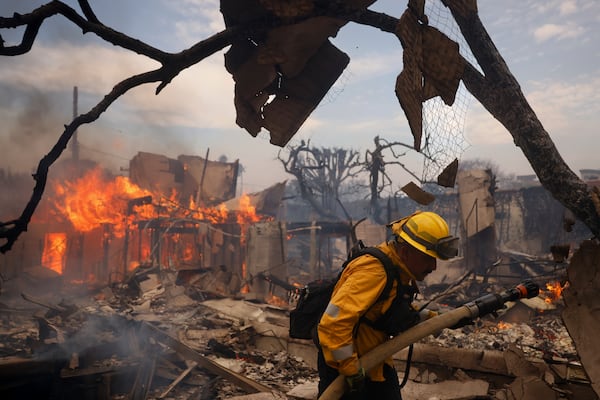 A firefighter battles the Palisades Fire around a burned structure in the Pacific Palisades neighborhood of Los Angeles, Wednesday, Jan. 8, 2025. (AP Photo/Etienne Laurent)