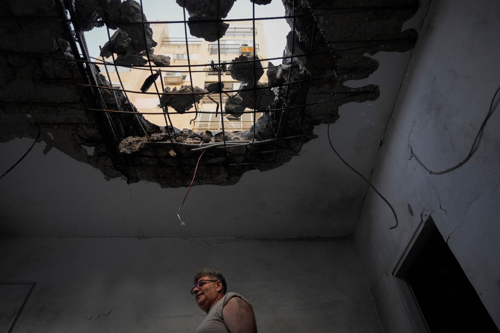 A man examine his damaged apartment that was hit by a rocket fired from Lebanon in Kiryat Yam, northern Israel, on Tuesday, Oct. 8, 2024. (AP Photo/Ariel Schalit)