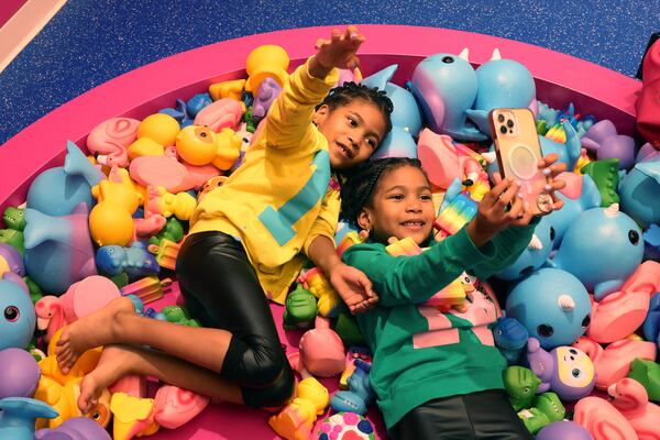 Seven-year-old twins Navali (yellow) and Nuri Barnes (green), of McDonough, play in the squishy play area of the slime-filed experience of Sloomoo in Buckhead, Wednesday, November 16, 2022, in Atlanta. Jason Getz / Jason.Getz@ajc.com)