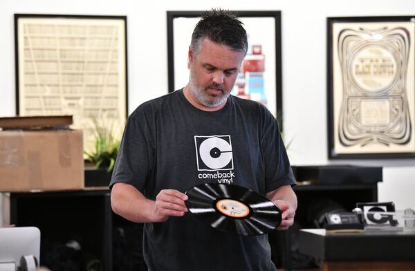 Connor Herrington inspects a used album before he packs a bag for a customer to pick up at Comeback Vinyl on Friday, May 8, 2020. Some local record shops are offering mail order and curbside pickup and a few are slowly reopening their doors to customers. (Hyosub Shin / Hyosub.Shin@ajc.com)