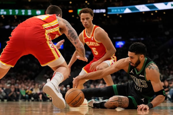 Atlanta Hawks' Garrison Mathews, left, and Boston Celtics' Jayson Tatum, right, scramble for the ball as Hawks' Dyson Daniels (5) moves in during the first half of an NBA basketball game, Saturday, Jan. 18, 2025, in Boston. (AP Photo/Robert F. Bukaty)