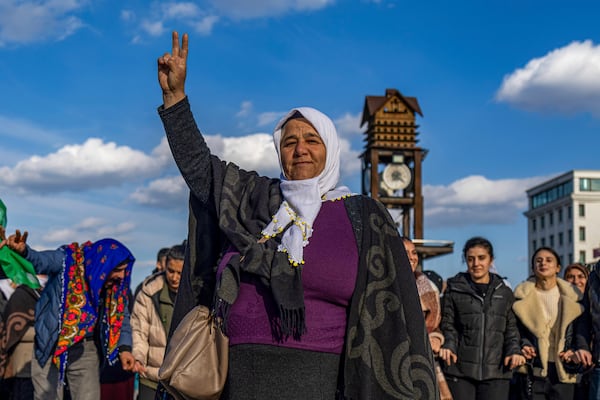 A Kurdish woman shows the V-sing as she gathers with others to watch live on a tv screen a Pro-Kurdish Peoples' Equality and Democracy Party, or DEM, delegation members releasing an statement from the jailed leader of the rebel Kurdistan Workers' Party, or PKK, Abdullah Ocalan, in Diyarbakir, Turkey, Thursday, Feb. 27, 2025. (AP Photo/Metin Yoksu)