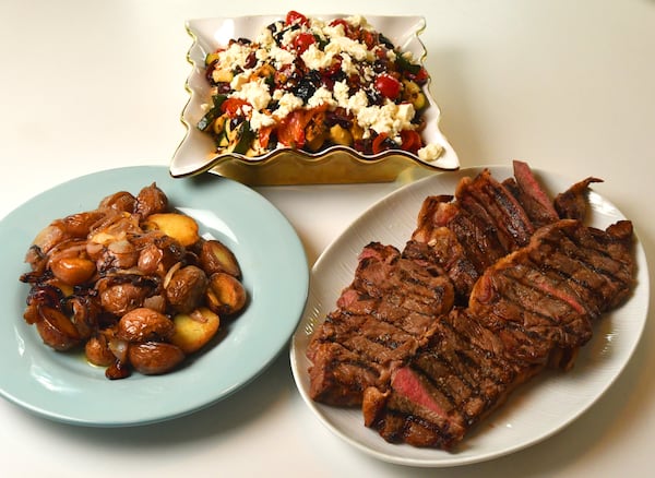 New York strip steaks (right) and Ciambotta Salad (top) are shown here with grilled potatoes and onions (left) as a side dish. (Styling by Pat Pascarella / Chris Hunt for the AJC)