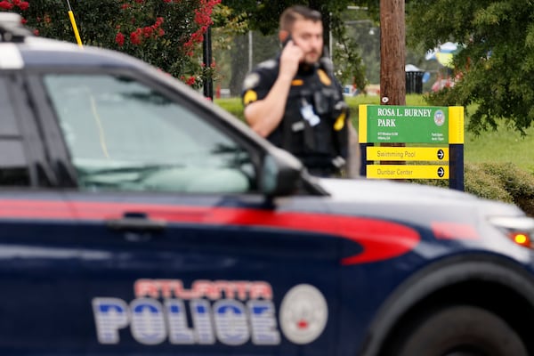 A police officer stands across the street from Rosa L. Burney Park Park on Monday, August 8, 2022, where gunfire Sunday evening left two people dead and four injured, including a 6-year-old girl. Miguel Martinez / miguel.martinezjimenez@ajc.com