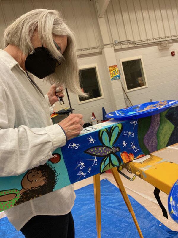 Faye Flowers Noble of the Avondale Artist Guild paints whimsical designs on one of the totem poles. Courtesy of Carolyn Chandler