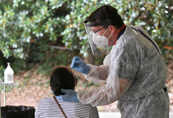 A medical worker wearing protective gear collects swabs from a student at COVID Surveillance Asymptomatic Testing center at Legion Field as the University of Georgia starts classes for the fall semester on Thursday, Aug. 20, 2020. (Hyosub Shin / Hyosub.Shin@ajc.com)