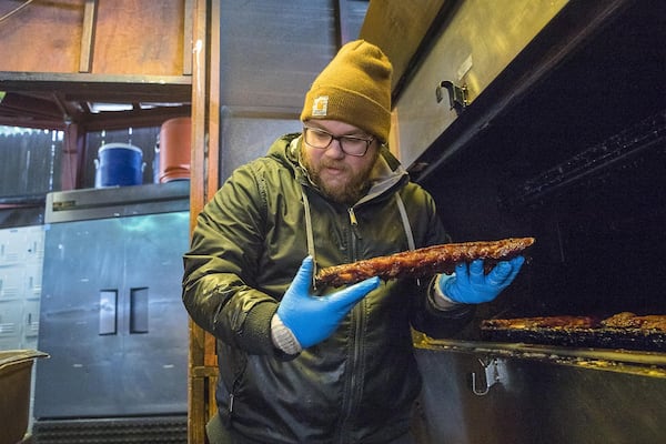 Smokehouse supervisor Craig Hoelzer handles a rack of ribs at Fox Bros. Bar-B-Q near Atlanta’s Little Five Points community. Fox Bros. Bar-B-Q is among many Atlanta restaurants getting ready for big business related to the Super Bowl. ALYSSA POINTER / ALYSSA.POINTER@AJC.COM