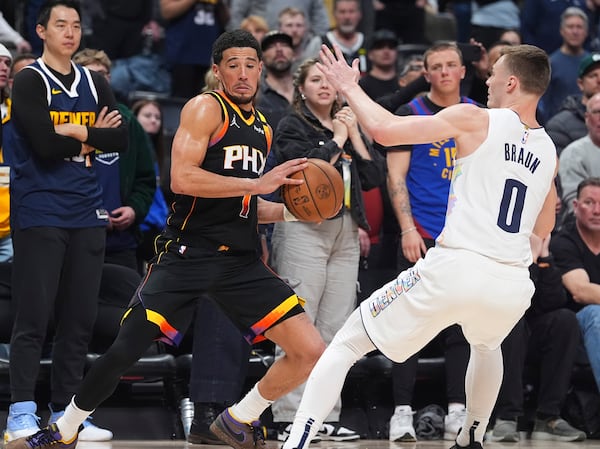 Phoenix Suns guard Devin Booker, left, collects a loose ball as Denver Nuggets guard Christian Braun defends in overtime of an NBA basketball game Friday, March 7, 2025, in Denver. (AP Photo/David Zalubowski)