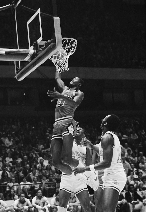 Georgia's Dominique Wilkins (21) slams the ball through the net as he dunks during SEC Basketball Tournament action against LSU in Birmingham, March 6, 1981. LSU's Burand Macklin looks up at the score. Georgia upset LSU 68-60. (AP Photo/Joe Holloway Jr.)