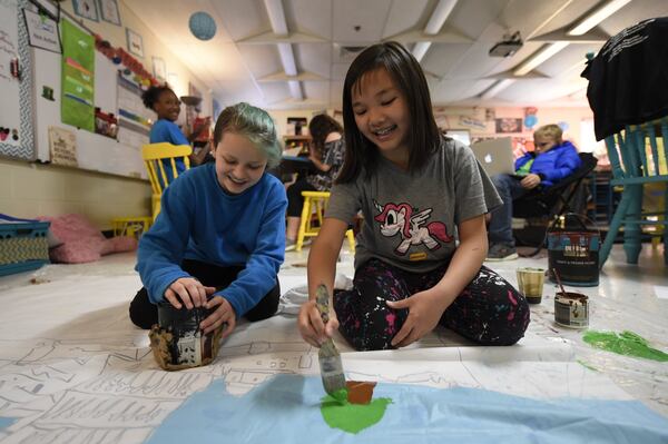 Macy Becigneul (left) and Kiki Chen paint a large piece of paper that will later become a window of the restaurant at the third annual Kitchen Kids Cafe, an event where the Advanced Learning class runs an Italian restaurant at their school to collect laundry detergent for the Save It Forward Program.