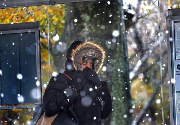 A lady covers her face at a Marta bus station as a wintry mix of sleet and snow is falling in East Atlanta Village. HYOSUB SHIN / HSHIN@AJC.COM