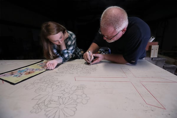 While daughter Lauren Clamp watches, Mart Clamp uses a precision knife to cut a stencil for the memorial he is making for his father, who, like his father before him, worked in the granite industry in Elberton. Curtis Compton/ccompton@ajc.com