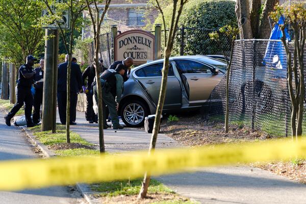 Police are seen at a scene where a man was found shot to death inside a sedan after it crashed into a fence at a southwest Atlanta apartment complex Friday.