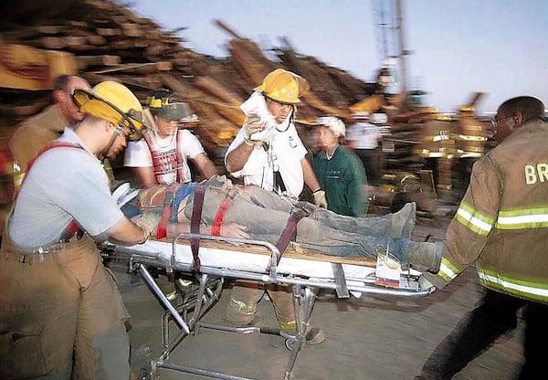 FILE - Emergency workers rush a student who was trapped for hours under a stack of logs which collapsed while being prepared for a pre-football game bonfire, Nov. 18, 1999, at Texas A&M University in College Station, Texas. (Dave McDermand/College Station Eagle via AP, File)